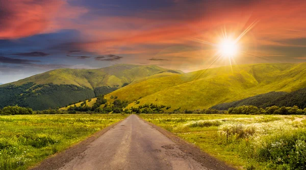 Verlaten weg door weiden in berg bij zonsondergang — Stockfoto