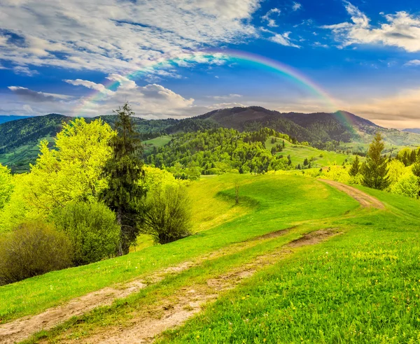 Road on hillside meadow in mountain at sunrise — Stock Photo, Image