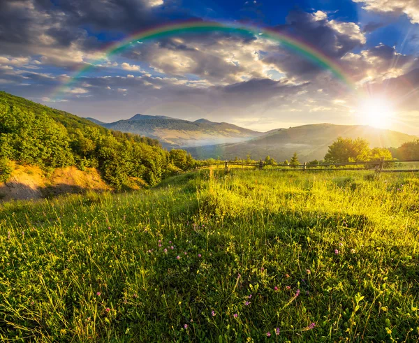 Fence on hillside meadow in mountain at sunset — Stock Photo, Image