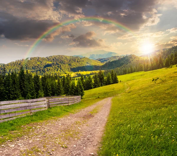 Fence on hillside meadow in mountain at sunset — Stock Photo, Image