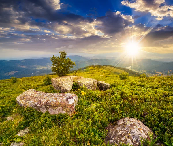 Boulders sur prairie à flanc de colline en montagne au coucher du soleil — Photo