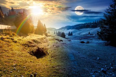 Sonbahar ekinoksunda güzel dağ manzarası. Gündüz ve gece zaman kavramını değiştirir. Doğal parktaki kozalaklı orman. Tepelerde çayırları olan kırsal vadide güneş ve ay var. şaşırtıcı kırsal