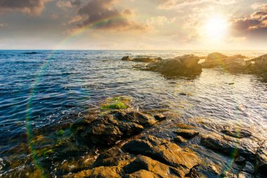 Gün batımında açık mavi gökyüzünün altında Karadeniz 'de kayalık bir sahilde hafta sonu. Yazın güzel bir sahil şeridi. Deniz manzarası, ufukta bulutlar var. güneşli hava