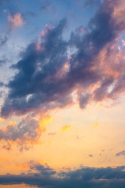 dark cloudscape at sunset. orange-purple clouds on a yellow-blue gradient of sky in evening light. dramatic weather change. wind forecast background. place for copy space. narrow telephoto shot