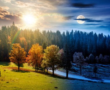 Sonbahar ekinoksu manzarası ormanın yakınındaki vadide yol boyunca renkli ağaçlarla. Gündüz ve gece zaman kavramını değiştirir. Dağlardaki güzel kır manzarası. Güneş ve ayın olduğu manzaralı bir yer.