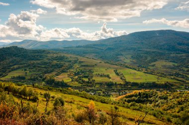 Dağlarda sonbahar manzarası. Avrupa 'nın güzel kırsal manzarası. Arka planda renkli Ukrayna Alpleri. Bulutlu gökyüzü. Vadideki köylü resimli kırsal manzara