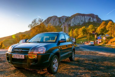 Bucces-Vulcan, Romanya - 12 Ekim 2019: Sonbaharda gün batımında dağ yolunda cip. Apuseni doğal parkının güzel dağlık manzarası. Avrupa 'da araba ülke dolaşmak