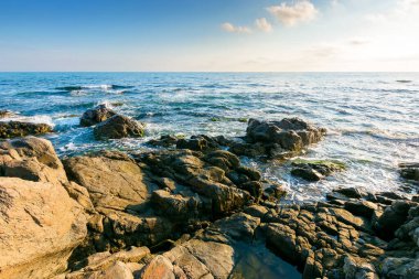 Açık mavi gökyüzünün altında, Karadeniz kıyısındaki kayalık bir sahilde hafta sonu. Yazın güzel bir kıyı şeridi. Ufkun üzerindeki bulutlarla aydınlık bir sabahta deniz manzarası. güneşli hava