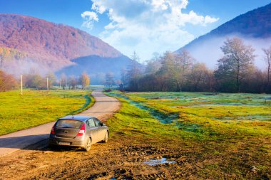 perechyn, ukraine - 10 nov 2020: car near asphalt road in autumn. trip through countryside mountain landscape of ukraine with morning fog. hyundai hatchback on the roadside near forest and field