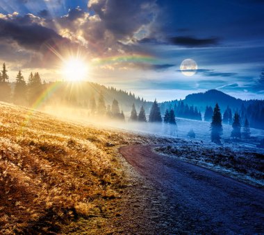 Sonbahar ekinoksunda dağ manzarası boyunca kırsal yol. Gündüz ve gece zaman kavramını değiştirir. Sis içinde yuvarlanan tepelerde kozalaklı orman. Güneş ve ay olan doğal park. güzel kırsal arkaplan