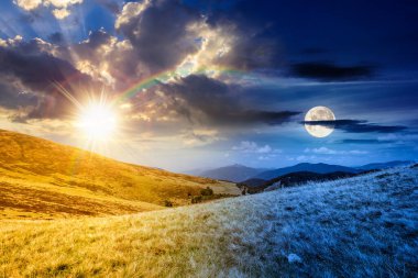 Çimenli tepe çayırları olan bir manzara. Gündüz ve gece zaman kavramını değiştirir. Yaz gündönümünde dağ manzarası. Alacakaranlıkta güneş ve ay. seyahat geçmişi. Doğa ikiliği ve geçiş şablonu