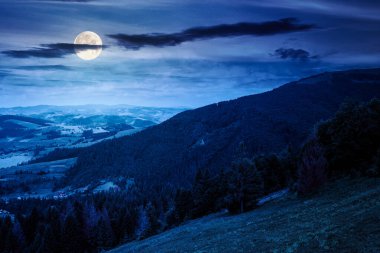 Geceleri bulutlarla dolu gökyüzü altında dağ manzarası. Çayır manzarası, dolunay ışığında yuvarlanan tepeler ve vadi. Yazın yürüyüş yeri. Yatırım veya soyut kavramlar için arkaplan