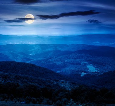 Geceleri tepeleri yuvarlanan dağ manzarası. uzak vadiyi gören ve dolunay ışığında orman yamaçları olan yaz kırsal manzarası. Yatırım finansmanı veya soyut kavramlar
