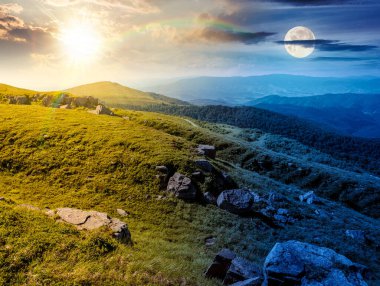 Yaz gündönümünde dağlarda yeşil alp çayırları. Gündüz ve gece zaman kavramını değiştirir. Alacakaranlıkta güneş ve ay olan çimenli tepelerde taşlar. Doğada ikilik ve geçiş şablonu. manzaralı yer
