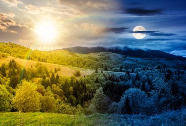 Dağ kırsalındaki orman. Gündüz ve gece zaman kavramını değiştirir. Alacakaranlıkta güneş ve ay olan bir yamaçta yeşil tarım arazisi. bahar ikiliği ve geçiş şablonu
