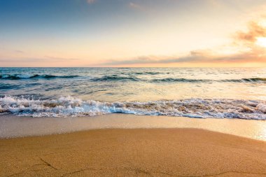 Yaz tatili konsepti için deniz kıyısındaki kumsal. Sakin dalgalar ve gökyüzünde bulutlarla mükemmel bir İspanya sahilinde güzel bir gün doğumu. Tatil ve seyahat geçmişi için güzel bir sabah manzarası