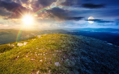Dağ kayaları olan çimenli yamaçlar. Gündüz ve gece zaman kavramını değiştirir. Alp yeşili gökyüzü altında güneşli ve aylı güzel yaz gündönümü manzarası. Uyum ve ilerleme takvimi