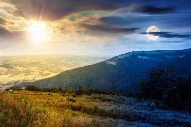 Mavi gökyüzünün altında bulutlu dağ manzarası. Gündüz ve gece zaman kavramını değiştirir. Yeşil çayırlı kırsal manzara, yuvarlanan tepeler ve güneşin ve ayın altındaki vadi. ikilik ve geçiş şablonu