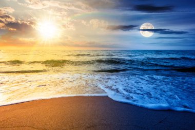 Yaz gündönümü tatili için deniz kıyısındaki kumsal. Gündüz ve gece zaman kavramını değiştirir. Sakin dalgalar, güneş ve ay ile mükemmel sahilde güzel bir gün doğumu. ikilik ve geçiş şablonu için manzara