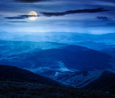 Geceleri tepeleri yuvarlanan dağ manzarası. uzak vadiyi gören ve dolunay ışığında orman yamaçları olan yaz kırsal manzarası. Yatırım finansmanı veya soyut kavramlar