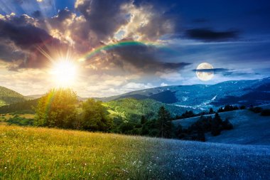 Yazın güzel dağ manzarası. Gündüz ve gece zaman kavramını değiştirir. Alacakaranlıkta güneş ve ay olan yuvarlanan tepelerde yabani otlarla otlak. Harika bir hava. Uyum ve ilerleme takvimi