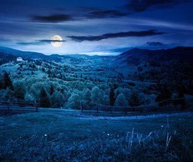 Dolunay ışığında dağlardaki ahşap çitler. İlkbaharda alp kırsalında. Bulutlu gökyüzü. kurgu sanatı veya gizem kavramları için arkaplan