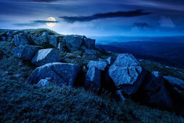Yazın dağ manzarası ve geceleri kayalar. Dolunay ışığında karanlık gökyüzünün altında çimenler. Alp çayırı ve kayalarla yuvarlanan tepeler. Şeytani kurgu sanatı veya gizemli kavramlar için arkaplan