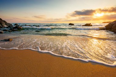 beautiful sunrise over empty sandy beach at the black sea. white foam rolling on to the shore near boulder. perfect summer vacation concept. awesome weekend from resort in sozopol. low angle