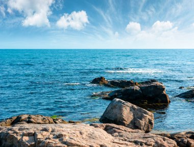 Deniz kıyısının kayalık kıyıları mavi gökyüzünün altında. Güneşli bir günde güzel bir kıyı manzarası. Tatil sezonunda Sozopol yakınlarındaki tatil yeri manzarası. Tatil için bir yer, geri çekilip kaçmak için.