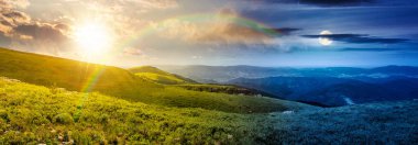 Yuvarlanan tepelerin dağlık manzarası. Gündüz ve gece zaman kavramını değiştirir. Uzak sıradağların üzerinde güneş ve ay ile harika bir hava var. Yaz gündönümünde Alp manzarasının destansı görüntüsü