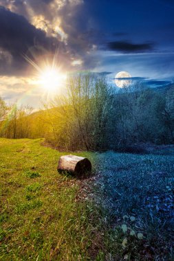 Baharda ormandaki yeşil çimlerle kaplı dağ manzarası. Gündüz ve gece zaman kavramını değiştirir. Gökyüzünün altında güneş ve ay olan kayın ağaçlarının olduğu güzel doğa manzarası. eşitlik ve kayma şablonu