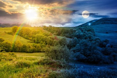 Vadinin kırsal kesiminde. Gündüz ve gece. Güneş ve ay yeşil kırsal alanda ağaçlık tepeler üzerinde. İlkbaharda dağ manzarası. Hava fotoğrafçılığı için uzak bir yer