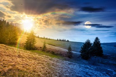 Baharda bulutlu gökyüzünün altında yeşil tarlaları olan yuvarlanan tepe. Gündüz ve gece zaman kavramını değiştirir. Alacakaranlıkta güneş ve ay olan dağların manzarası. eşitlik ve kayma şablonu