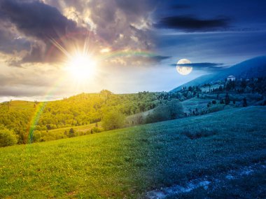 Dağ manzarasının kırsal kesimi. Gündüz ve gece değişiyor. Baharda güneşli ve aylı sisli bir hava. Bir tepedeki yemyeşil otlaktan geçen toprak yol. Yaprak döken ağaçları olan alp manzarası