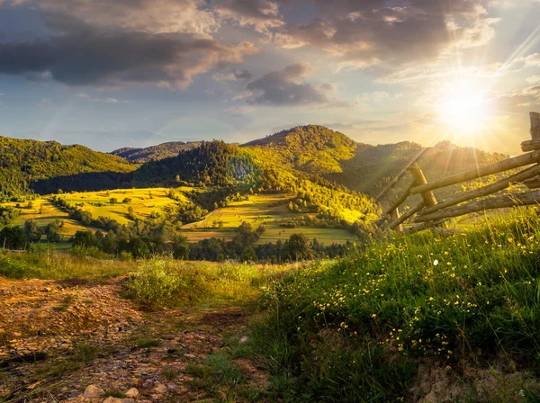 Cerca de madera en la hierba en la ladera al atardecer —  Fotos de Stock