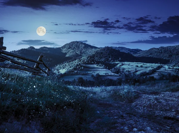 夜に丘の中腹に草で木製フェンス — ストック写真