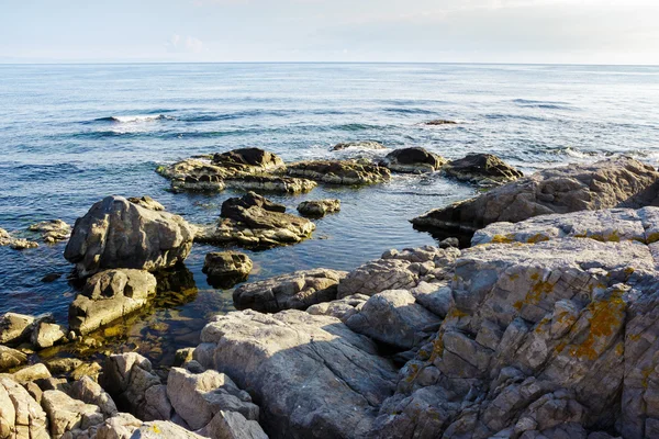 Onde marine si infrangono sulla riva rocciosa all'alba — Foto Stock