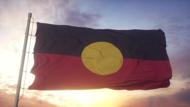 Австралийский флаг аборигенов, размахивающий на фоне ветра, неба и солнца — стоковое видео