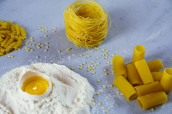 Ingredients for homemade pasta. Food background: macaroni, spagetti, egg, flour — Stock Photo, Image