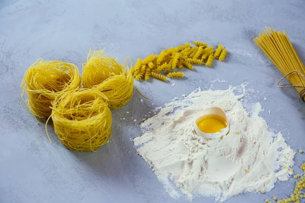 Ingredients for homemade pasta. Food background: macaroni, spagetti, egg, flour — Stock Photo, Image