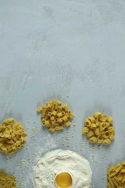 Ingredients for homemade pasta. Food background: macaroni, spagetti, egg, flour — Stock Photo, Image