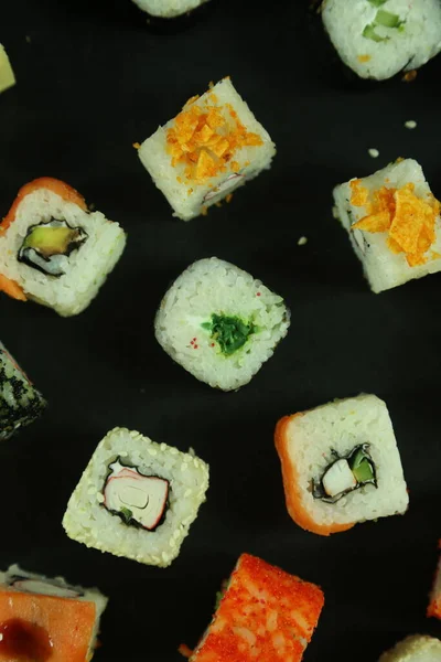 Sushi z łososiem, tuńczykiem, awokado i ogórkiem. Dużo bułek. Bułki sushi. — Zdjęcie stockowe