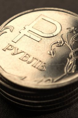 Parlak parlayan Rus 1 1 ruble sikkesi. Üzerinde ulusal para biriminin resmi sembolü var. Çok karanlık, neredeyse siyah bir arkaplan. Sarı ya da altın renkli dikey illüstrasyon. Rus ekonomisi ve finans