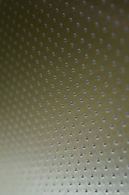 Zeytin ya da bronz renkli endüstriyel dikey arka plan. Birçok deliği olan metal bir yüzey delinmiş. Safları mesafeye çekiliyor ve bir perspektif oluşturuyor. Soyut alüminyum arkaplan veya duvar kağıdı