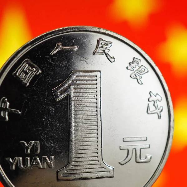 Chinese money. 1 one yuan coin close-up against the background of the blurred PRC flag. Square illustration. China\'s economy, national currency rate, devaluation, trade war, export, import