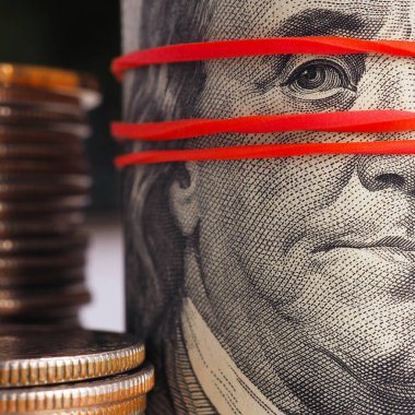 Franklin portresi olan eski 100 dolarlık banknot. Banknot elastik bir bant tarafından çekiliyor ve maske gibi yüzünden. Kayıt dışı para masanın altında. Kare atış. Güçlü makro