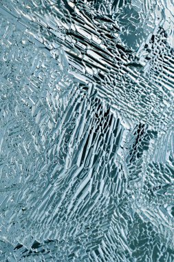 Buz kristalleri bir pencere camının üzerine kapanır. Donmuş su. Mistik muhteşem soyut desen. Kış, Noel ve Yeni Yıl teması için dikey zemin. Mavi şeffaf arkaplan ya da duvar kağıdı. Makro
