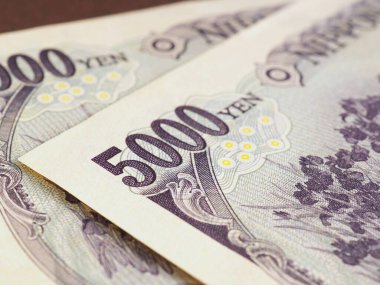 Japon 5000 yenlik banknotlar kahverengi bir yüzeye yakın duruyor. Bankalar, finans ve Japonya ekonomisi temalı bir illüstrasyon. Makro