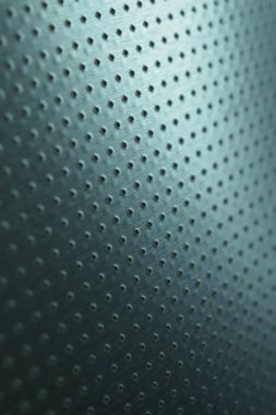 Karanlık, dikey endüstriyel duvar kağıdı. Renkli mavi-yeşil metal arka plan. Birçok deliği olan delinmiş alüminyum yüzey. Makro