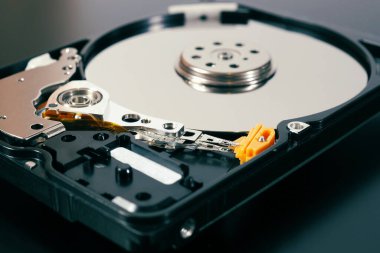 Bir bilgisayarın ya da dizüstü bilgisayarın parçalanmış bir sabit disk sürücüsü. Cihaz koyu bir mat yüzeyinde bulunuyor. IT & C, bilgisayar donanımı ve ekipmanları hakkında renkli çizimler. Makro